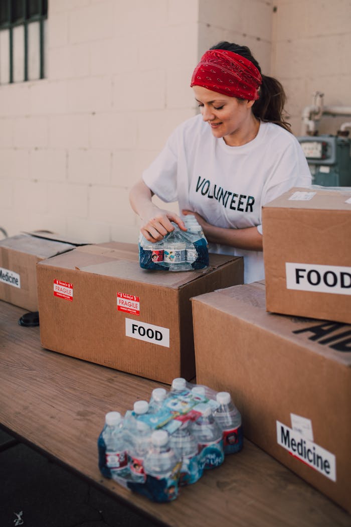 our-experience Volunteer packing food and water for charity at an outdoor event, emphasizing community support.