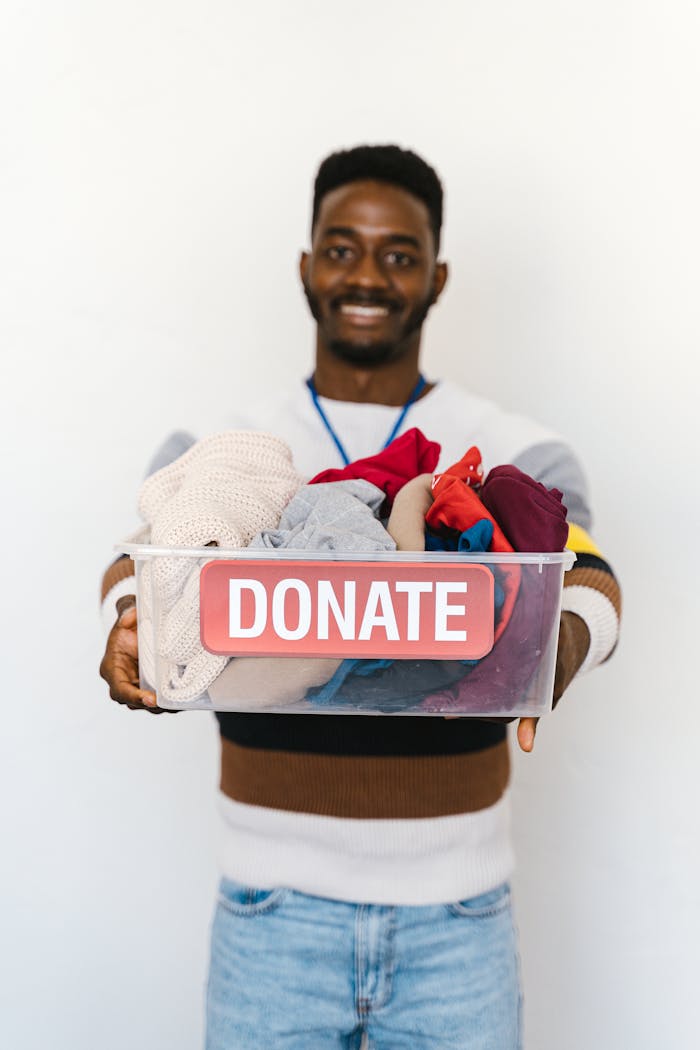 contact-img A cheerful volunteer holds a donation box filled with clothes, encouraging charitable giving.