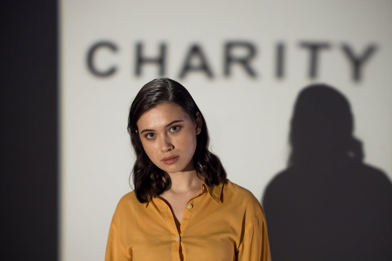 services-01 A thoughtful woman stands before a charity-themed backdrop, evoking compassion and volunteerism.